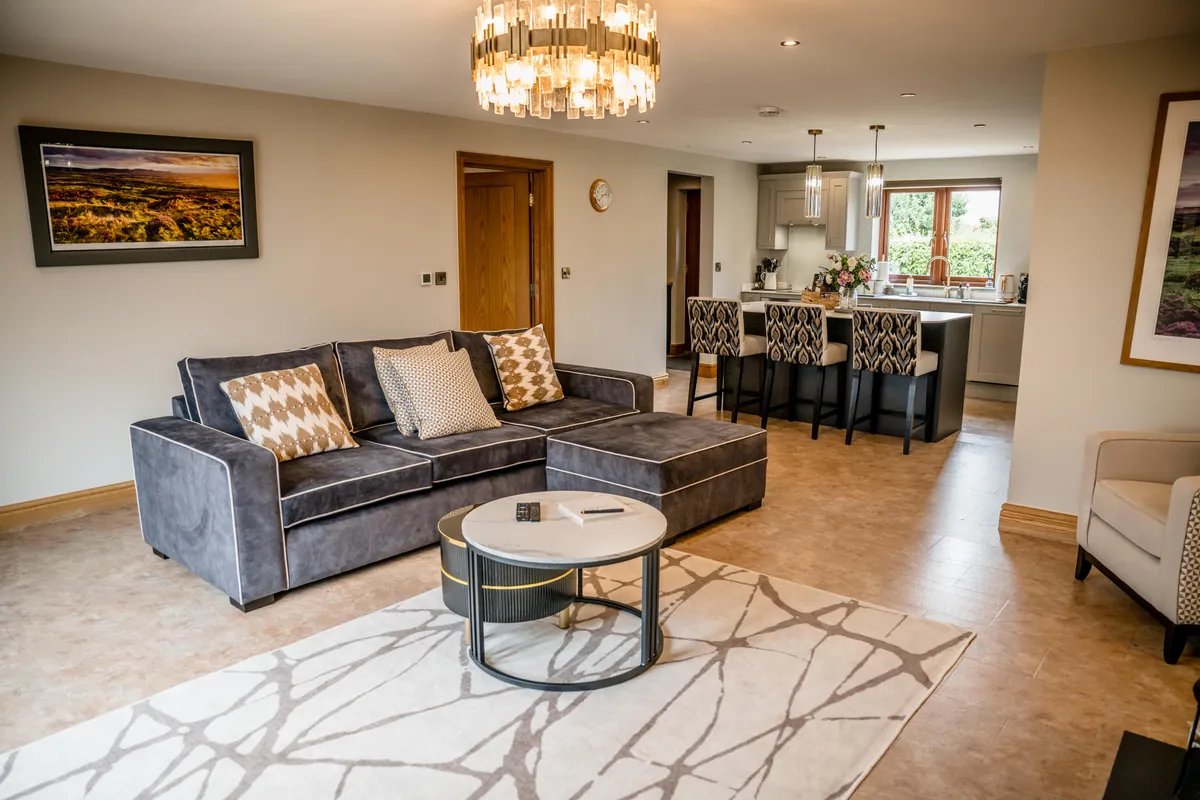 A corner sofa, chandelier and kitchen in Bateman Byre