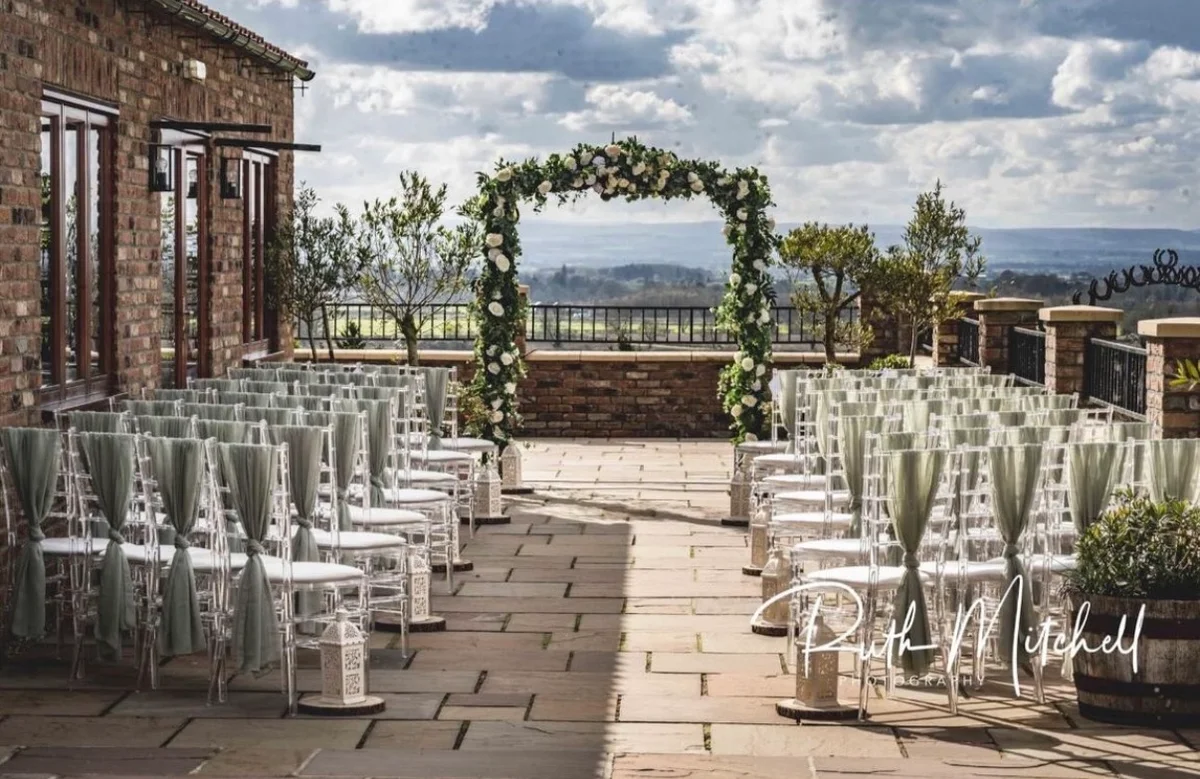 Patio ceremony chairs facing a flower-covered arch and North Yorkshire views