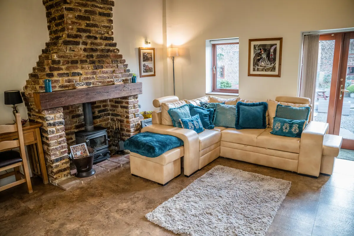A cottage living room with an exposed brick chimney and log burner