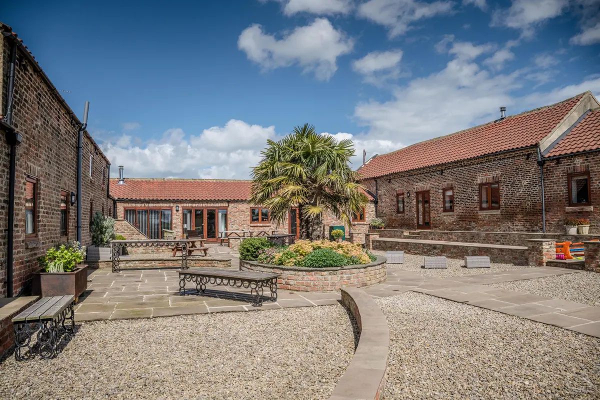 The paved cottage courtyard enclosed by Thief Hall's brick barn ranges