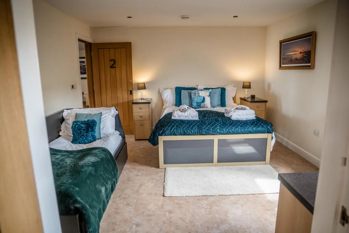 A prepared cottage bedroom with folded robes on the beds