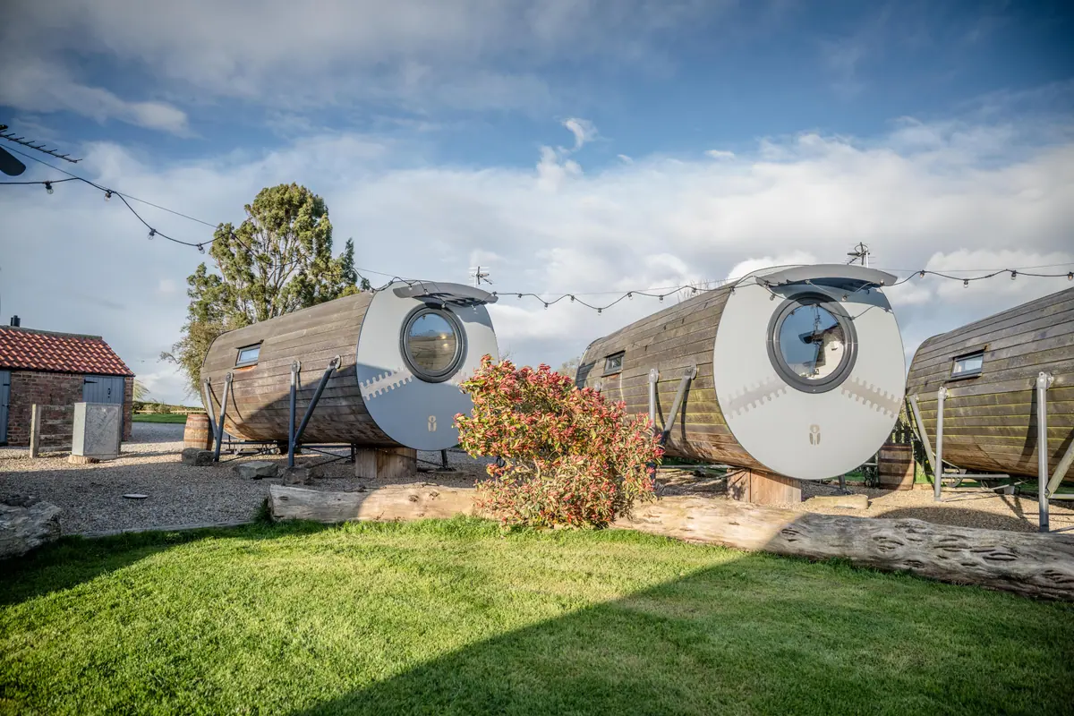 Timber glamping pods beside the lawns at Thief Hall